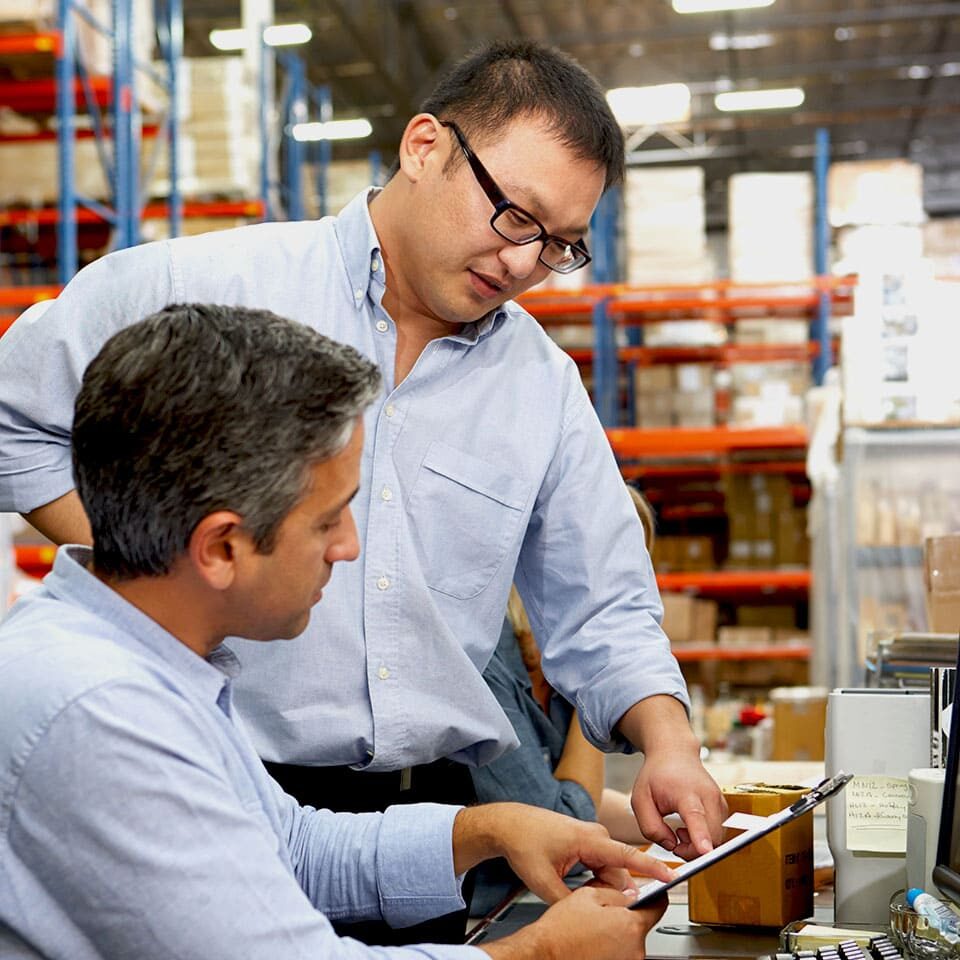 Business Colleagues Working At Desk In Warehouse Business Colleagues Working At Desk In Warehouse